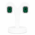 Pair of emerald green square gemstone earrings on a white stand.