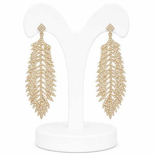 Gold leaf-shaped earrings on a white stand with a white background