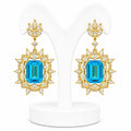 Pair of gold earrings with blue gemstones on a white background