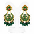 Pair of green and gold earrings on a white stand