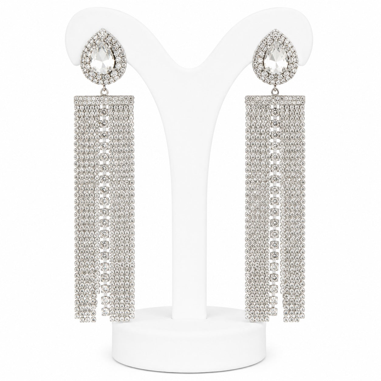 Silver teardrop earrings with dangling crystals on a white stand.