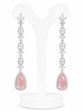 Pair of pink teardrop earrings with silver and diamond accents on a white stand.