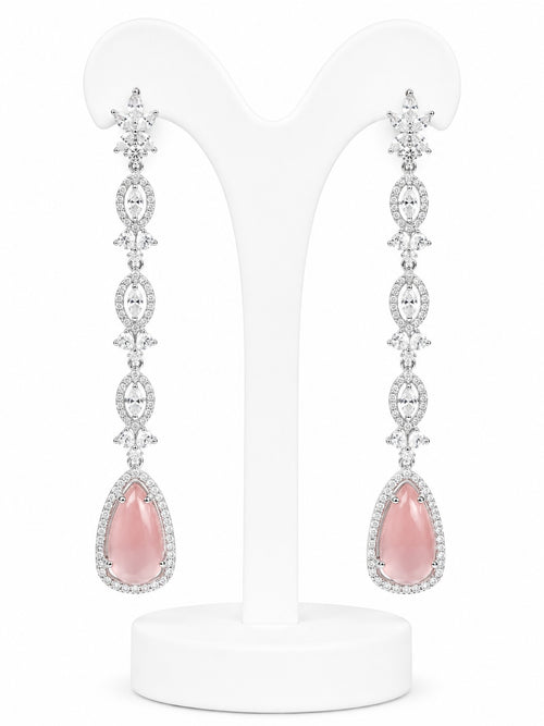 Pair of pink teardrop earrings with silver and diamond accents on a white stand.