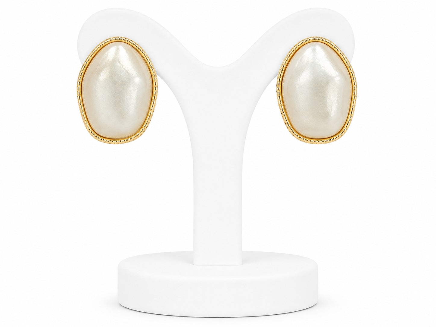 Pair of pearl earrings with gold accents on a white stand.