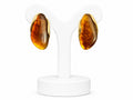 Pair of amber-colored earrings on a white stand against a white background