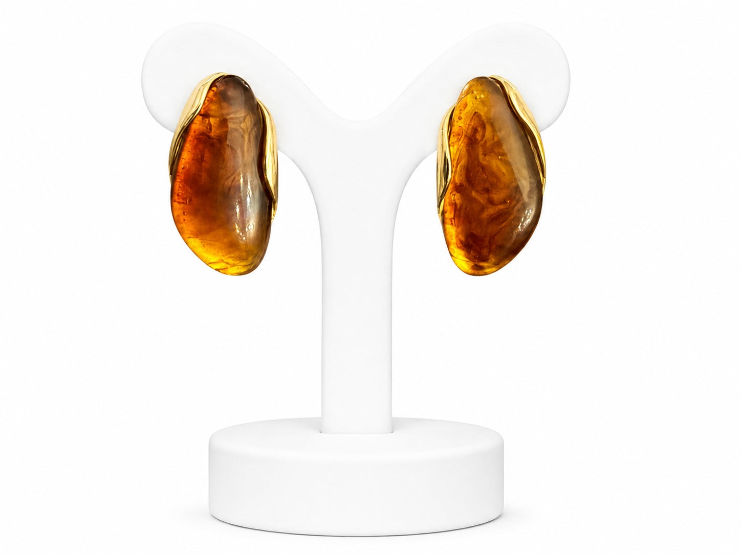 Pair of amber-colored earrings on a white stand against a white background