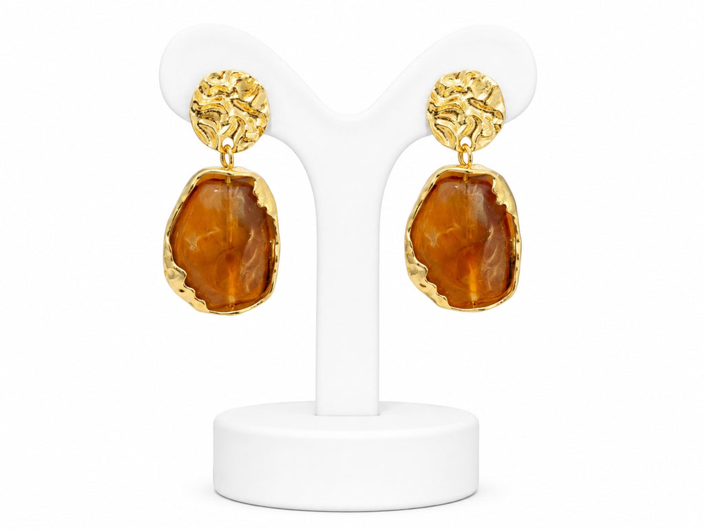 Gold earrings with brown stone drops on a white stand