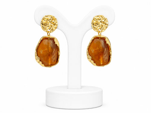 Gold earrings with brown stone drops on a white stand