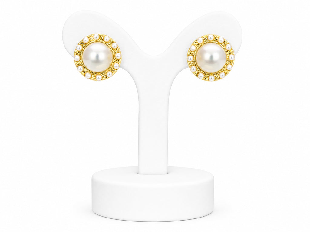 Pair of pearl earrings with gold accents on a white stand
