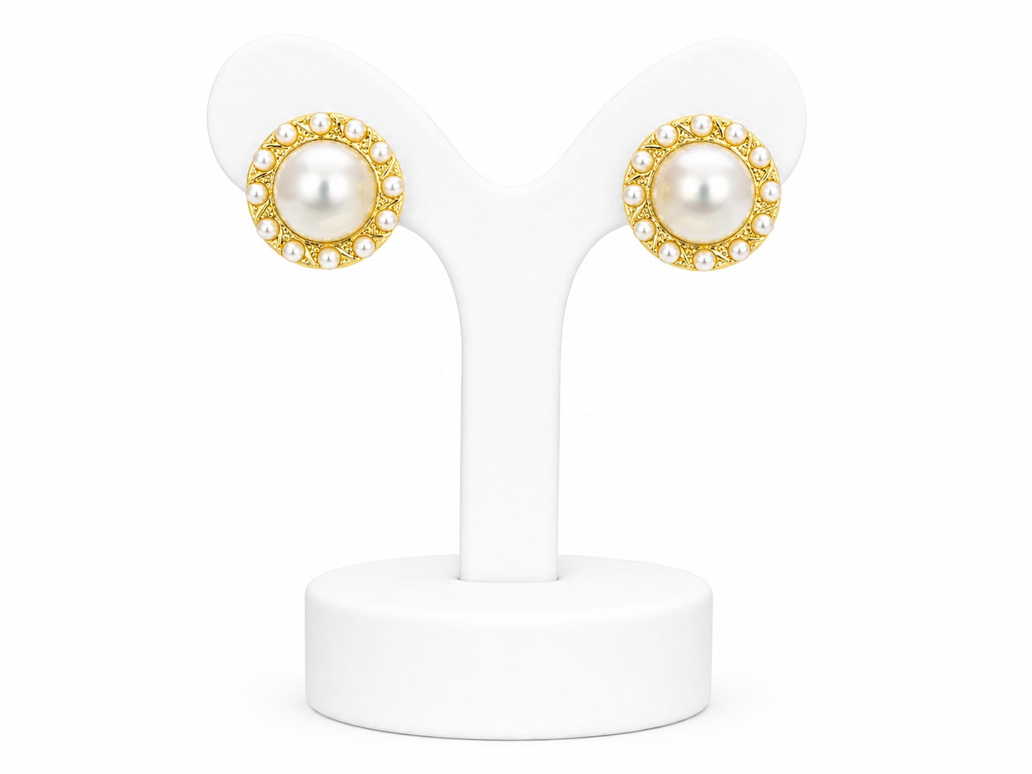 Pair of pearl earrings with gold accents on a white stand