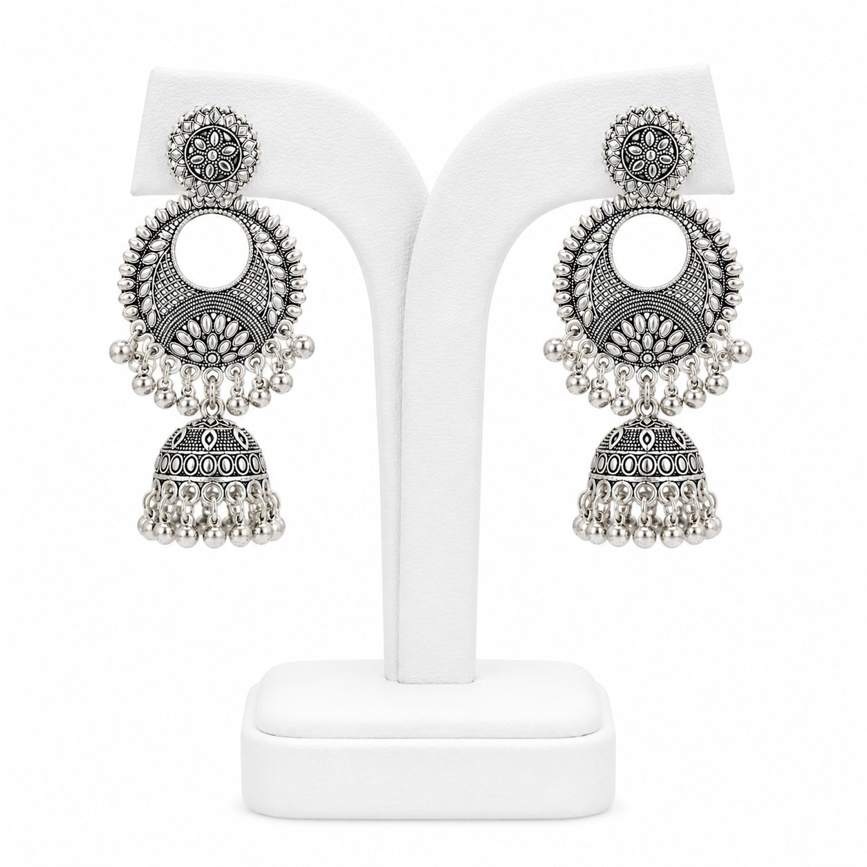 Pair of silver earrings on a white stand with a white background