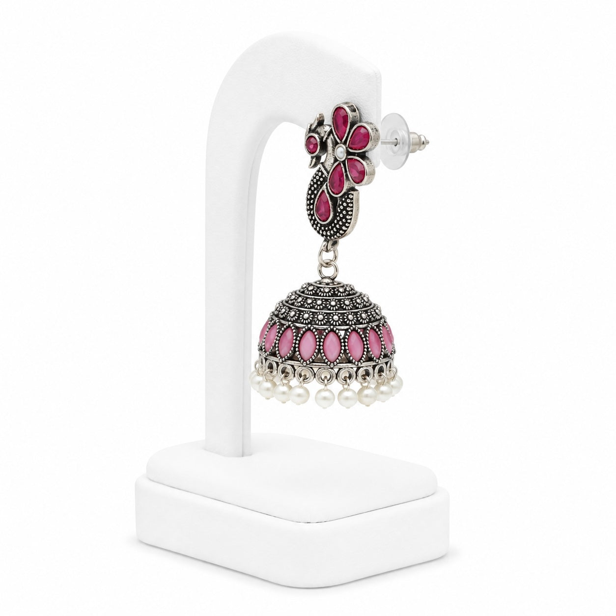 Ornate earring with pink stones and pearl-like beads on a white stand