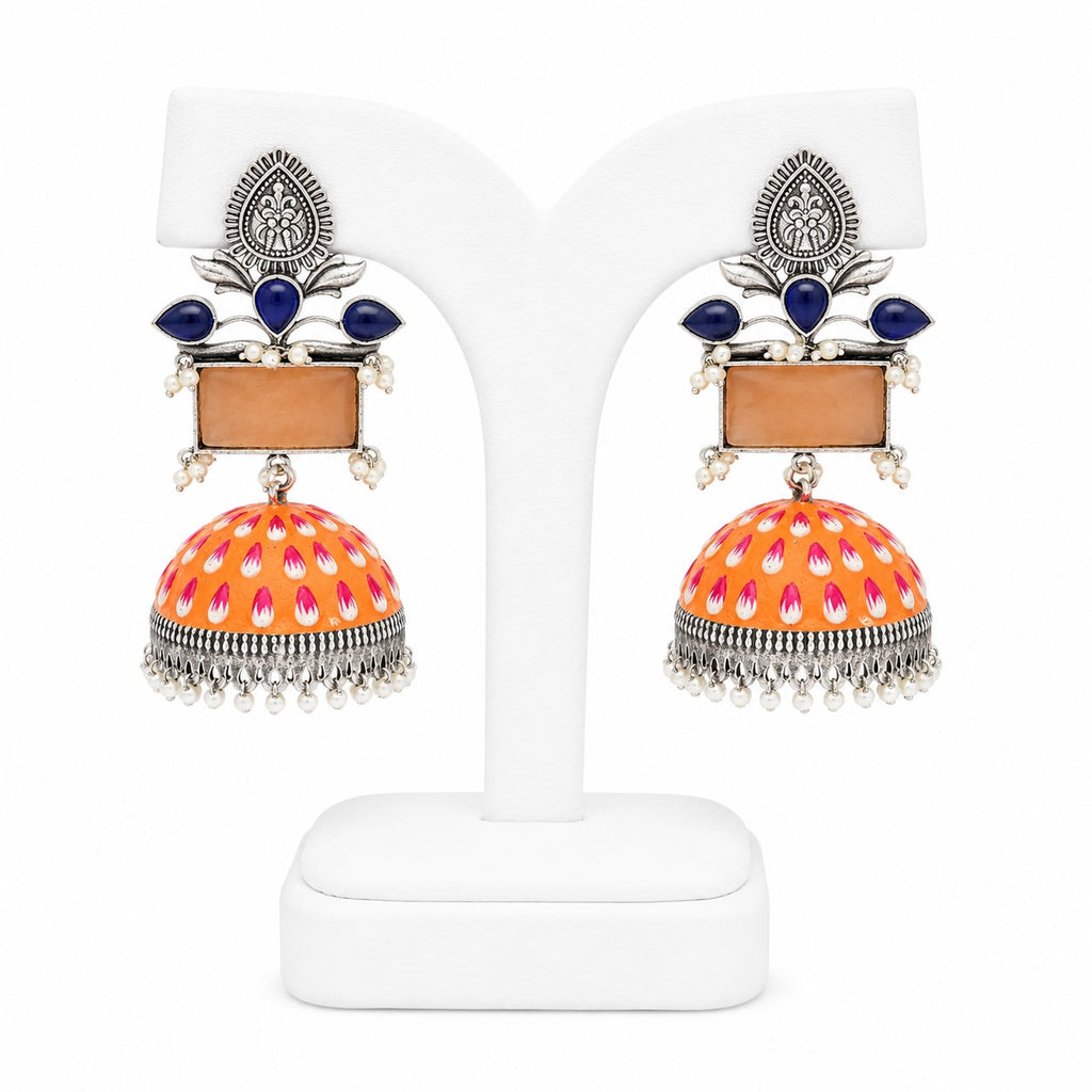 Colorful earrings with orange and pink design on a white stand