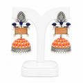 Colorful earrings with orange and pink design on a white stand
