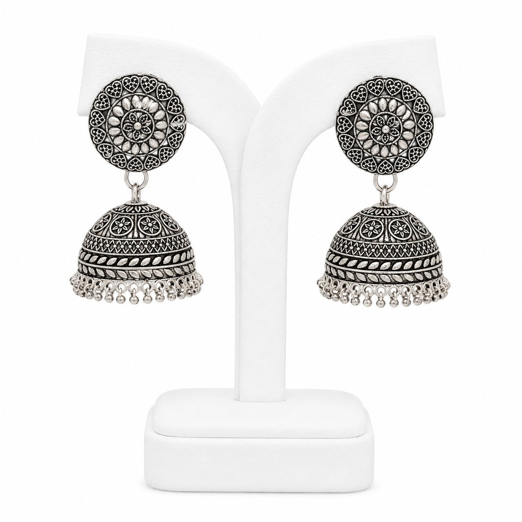 Pair of silver jhumka earrings on a white stand