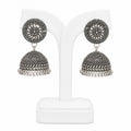 Pair of silver jhumka earrings on a white stand