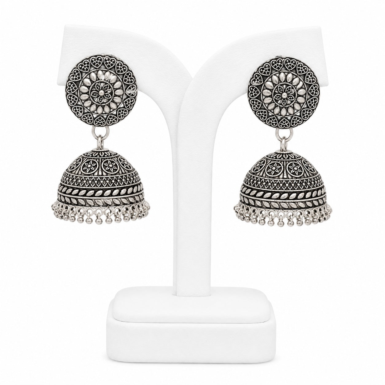 Pair of silver jhumka earrings on a white stand
