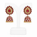 Pair of red and gold earrings on a white stand