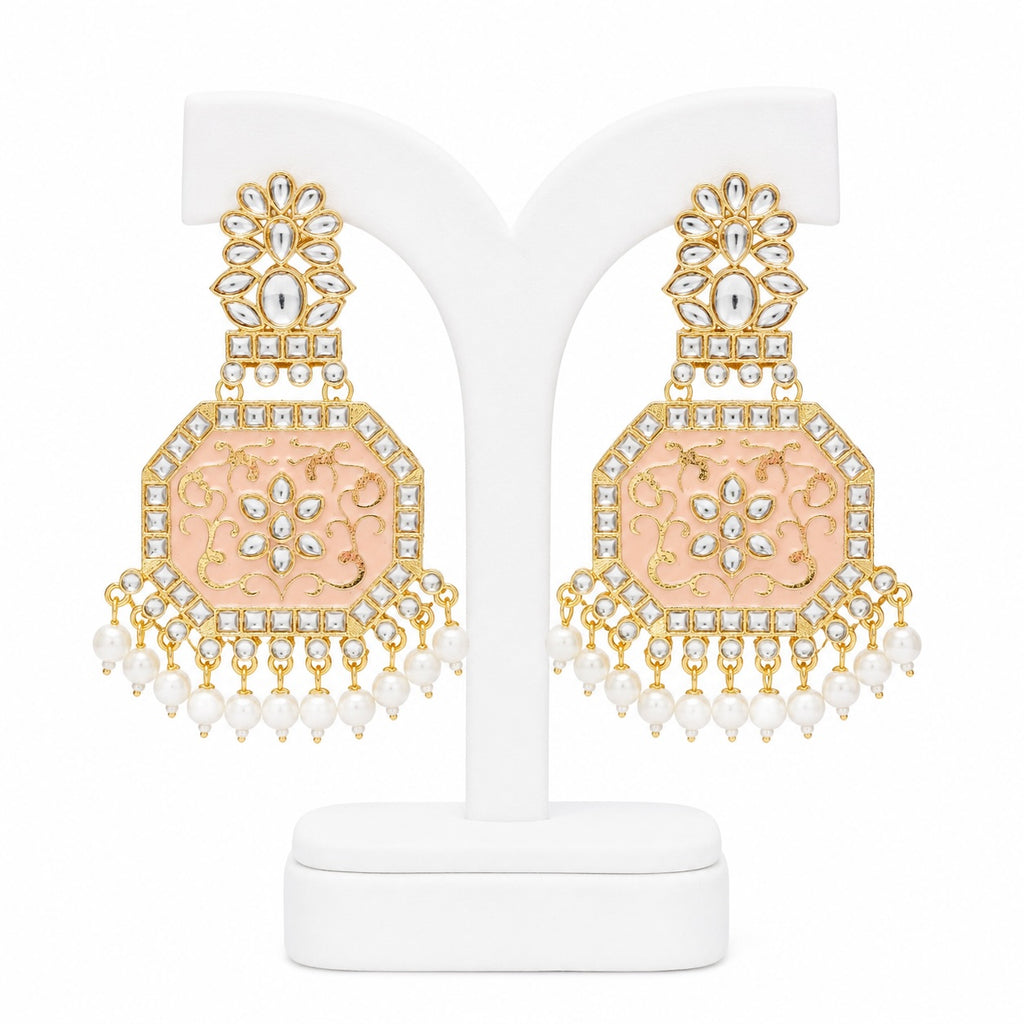 Ornate earrings with gold and pink design on a white stand