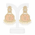 Ornate earrings with gold and pink design on a white stand