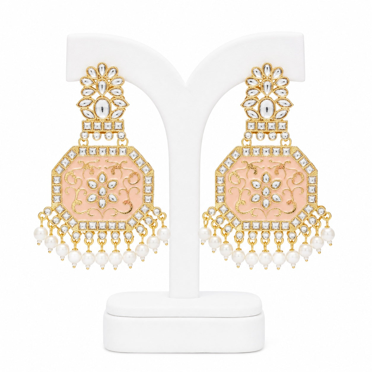 Ornate earrings with gold and pink design on a white stand