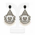 Pair of silver earrings with black stones and pearl-like beads on a white background