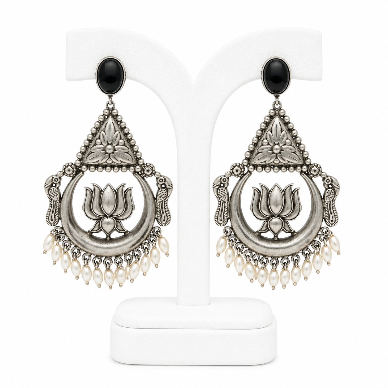 Pair of silver earrings with black stones and pearl-like beads on a white background