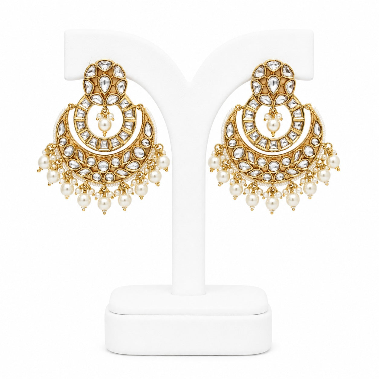 Gold and pearl earrings on a white stand