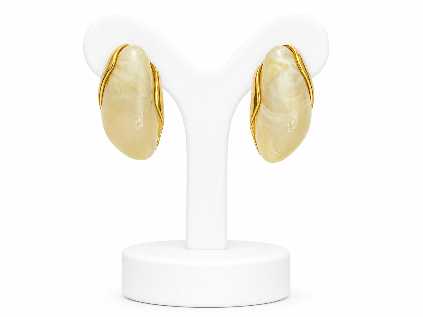 Pair of gold earrings on a white stand against a white background