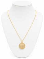 Gold necklace with a circular pendant on a white mannequin bust.