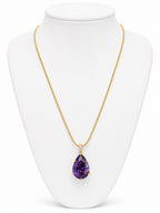 Gold necklace with a purple teardrop pendant on a white mannequin bust.