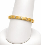Gold ring with diamond accents on a white stand