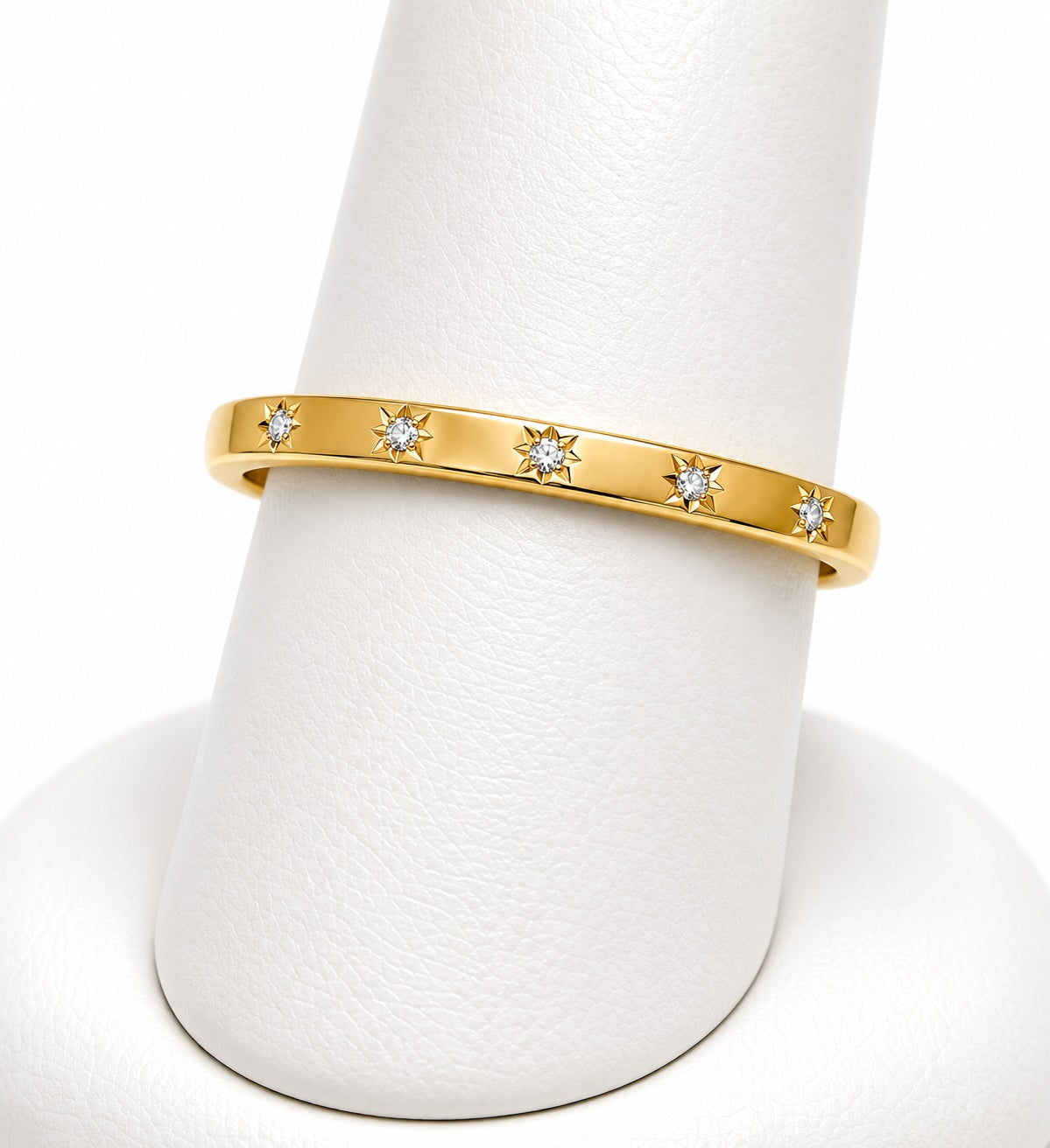 Gold ring with diamond accents on a white stand