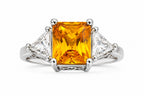Ring with a yellow gemstone and triangular diamonds on a white background
