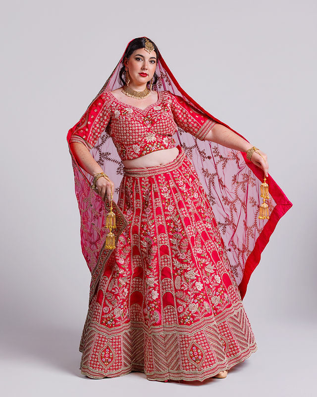Woman wearing a red and gold embroidered traditional outfit with a matching dupatta on a white background
