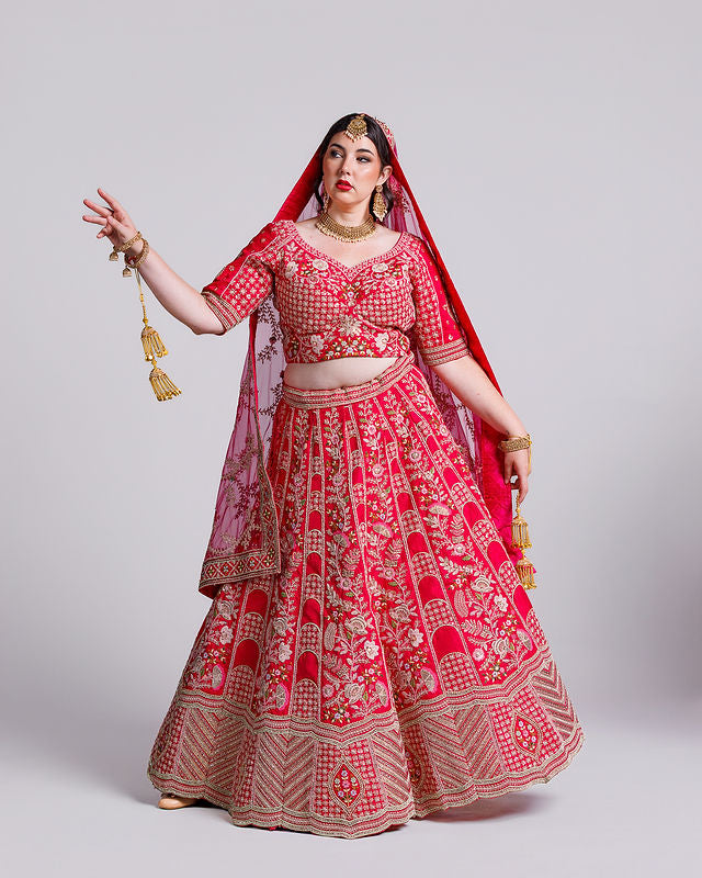 Woman wearing a traditional red and gold embroidered outfit on a light gray background