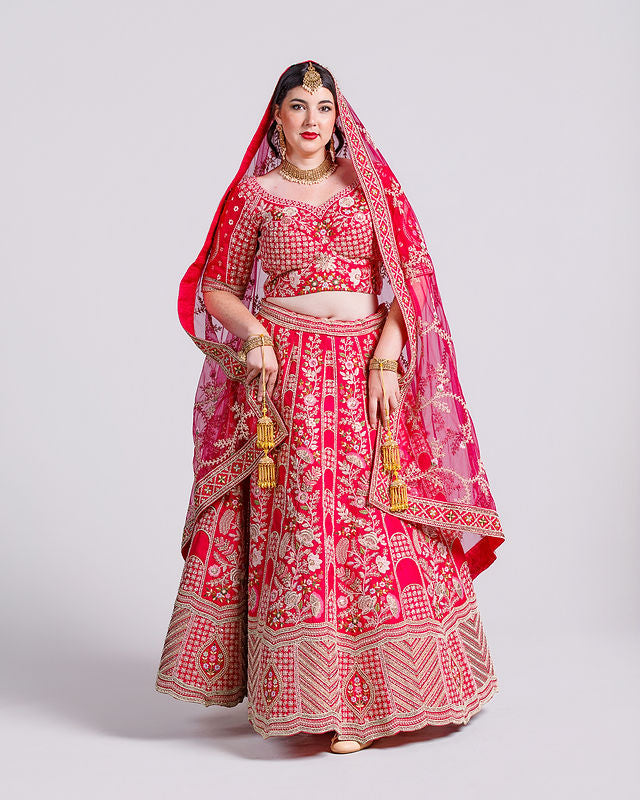 Woman wearing a traditional red and gold embroidered outfit with a matching dupatta on a white background